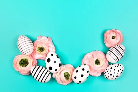 Creative graphic eggs and ranunculus flowers on blue pastel background. Stock Photos
