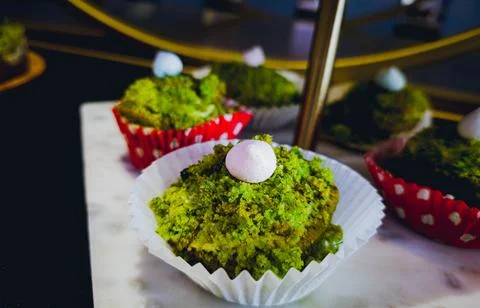 Creative green muffin decorated with mini meringue on marble stand Stock-Fotos