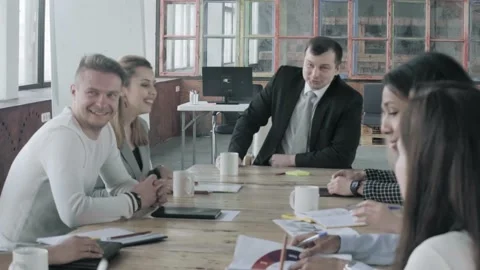 A creative group of managers sits at a table with a leader during a break and Stock Footage 134160605