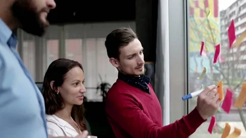 Creative group writing and sticking notes on glass board Video stock 134182146