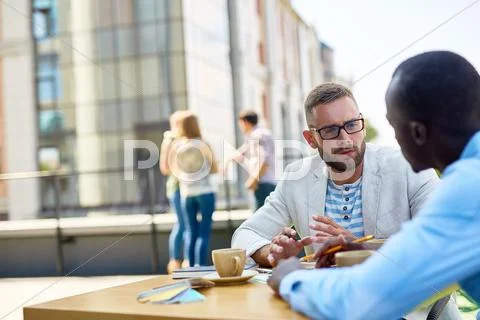 Creative guy talking to co-worker in urban environment Stock Photos