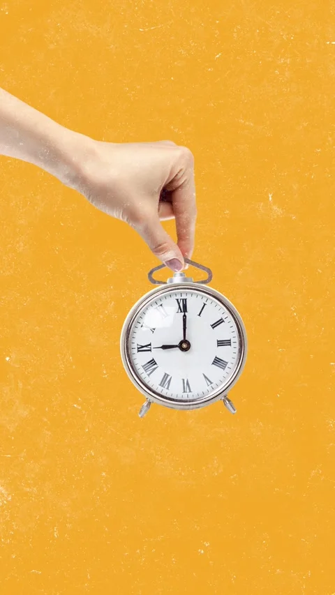 Creative hand holding an antique clock against a bright orange background during 動画素材 322550114