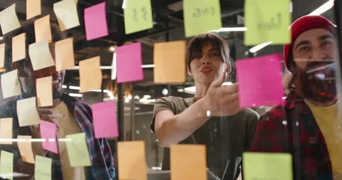 Creative hipster multiethnic team brainstorming near strategy board with 動画素材 154768472