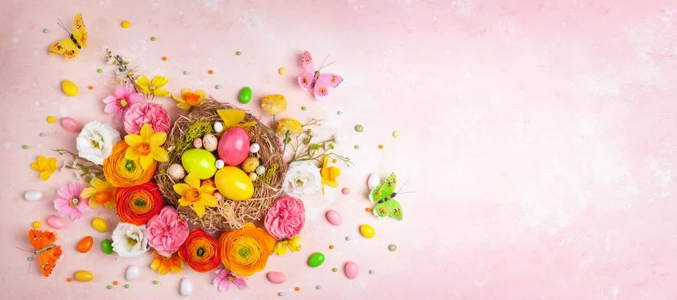Creative holiday concept with easter eggs in nest, spring flowers and candy Stock Photos