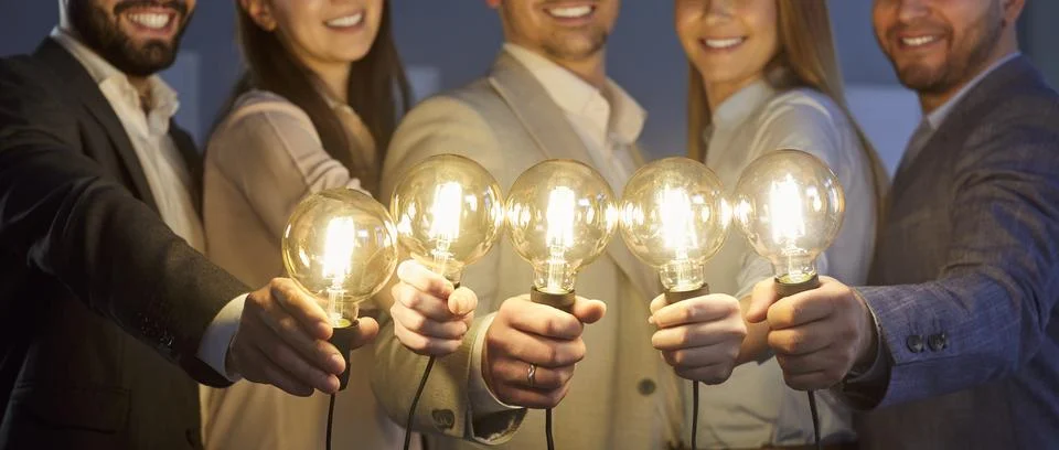 Creative idea and work of happy business team holding bright light bulbs and Stock Photos