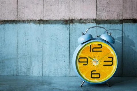 Creative idea layout fresh orange slice alarm clock on wooden table with blue Stock Photos