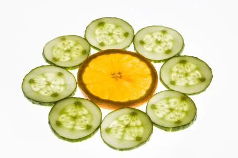 Creative image of orange slice surrounded by cucumbers in form of flower Stock Photos