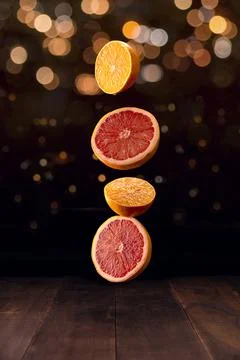 Creative image of ripe orange and grapefruit slices falling on brown rustic w Foto stock