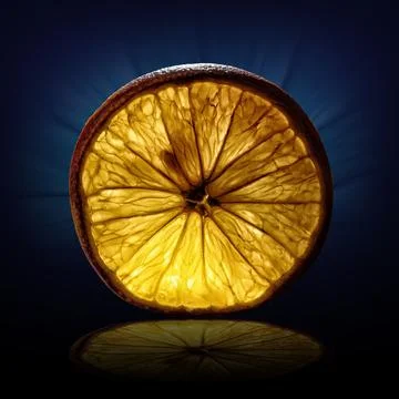 Creative image of a slice of orange view on backlight on dark blue background Stock Photos