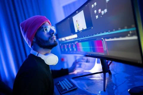 Creative individual engaged in video editing using dual monitors in a moder.. Stock Photos