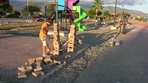 Creative kid busy building towers with bricks near children playground Stock Footage 164036166