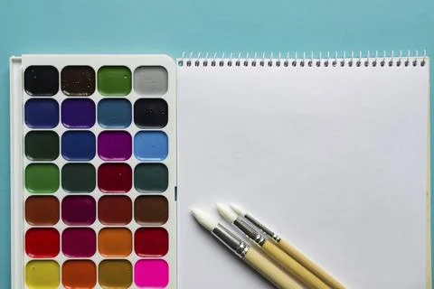 Creative layout with aquarelle palette, paint brushes on blue background. Top Stock Photos