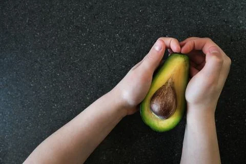 Creative layout of avocados in hands on a dark background. Food concept. Stock Photos