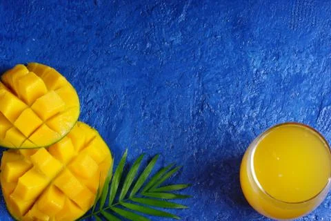 Creative layout on a blue background with mango, a glass of juice and a palm  Stock Photos