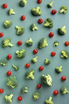Creative layout of broccoli, tomatoes on green paper background. Top view. Food Stock Photos