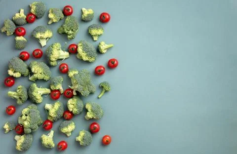 Creative layout of broccoli, tomatoes on green paper background. Top view. Food Stock Photos