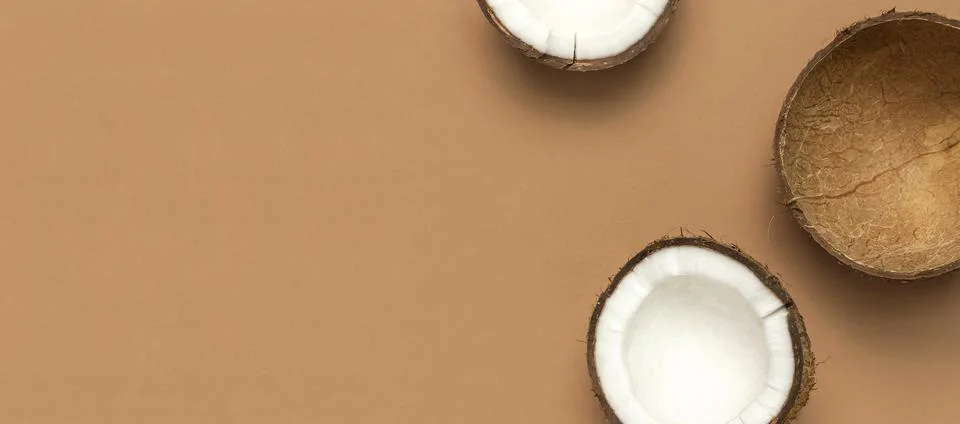 Creative layout with coconuts. Whole and half coconut on brown background Stock Photos