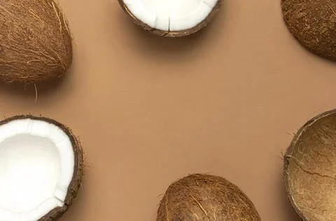 Creative layout with coconuts. Whole and half coconut on brown background Stock Photos
