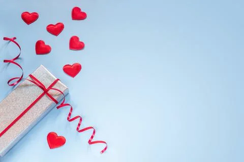 Creative layout with gift box and red fabric hearts on blue background Stock Photos