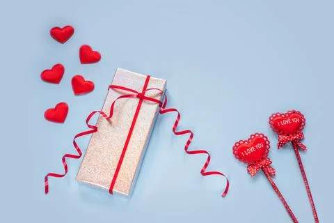 Creative layout with gift box and red fabric hearts on blue background Stock Photos