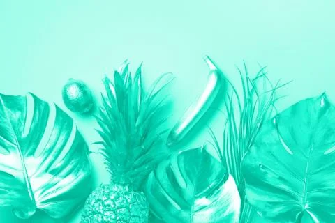 Creative layout. Gold pineapple and palm, monstera on mint color background with Stock Photos