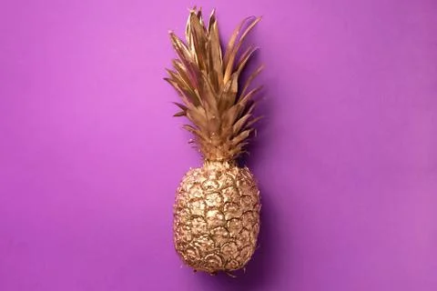Creative layout. Gold pineapple on violet background with copy space. Top view Stock Photos