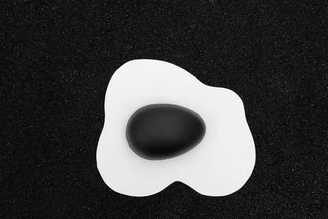 Creative layout made of scrambled egg with painted black half Easter egg on a Stock Photos