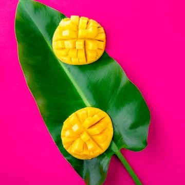 Creative layout made of summer tropical fruits mango and tropical leaves on pink Stock Photos