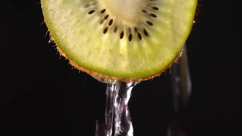 Creative layout of sliced kiwi and water. Splashes on black background. Stock Footage 248782489