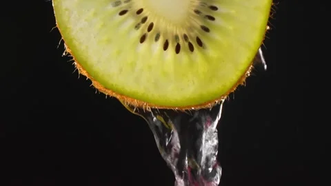 Creative layout of sliced kiwi and water. Splashes on black background. Video stock 248783984