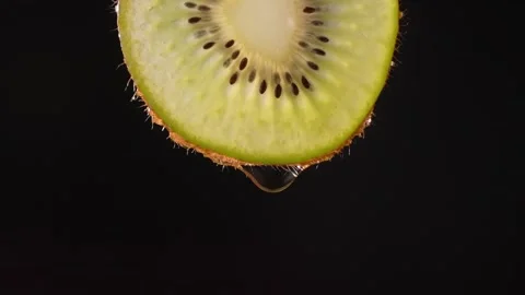 Creative layout of sliced kiwi and water. Splashes on black background. Stock Footage 248893484