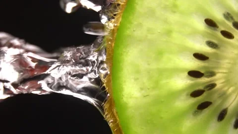 Creative layout of sliced kiwi and water. Splashes on black background. 库存影片 251910681