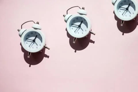 Creative layout of white alarm clock's on pastel pink background. Minimal 写真素材