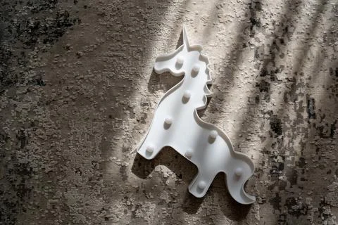 Creative light effect, sunbeam stripes on grey background, white unicorn toy Stock Photos