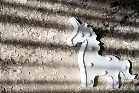 Creative light effect, sunbeam stripes on grey background, white unicorn toy Stock Photos
