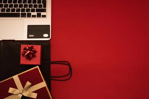 Creative look, red gift box, laptop, credit card and black package on red Stock Photos