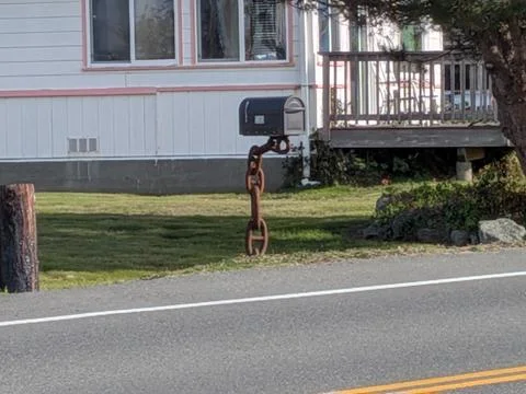 Creative mailbox perched on heavy rusty chain pole Stock Photos