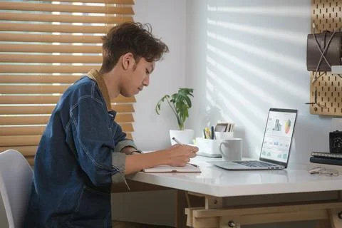 Creative male freelancer sitting at desk front of laptop computer and makin.. Stock Photos