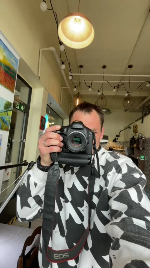 Creative male photographer documenting himself in warm cafe setting Stock Footage 335434854