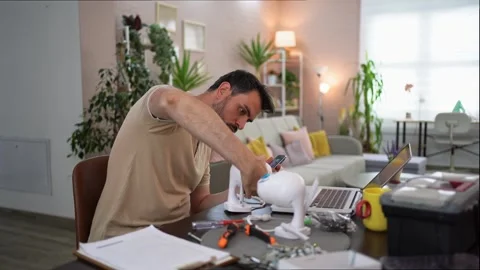 Creative man assembling a gadget in a cozy home workspace Stock Footage 289573911