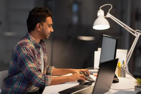 Creative man with computer working at night office Stock Photos