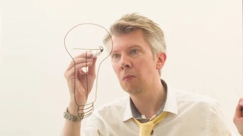 Creative man drawing a lightbulb onto glass against a blank background Stock Footage 80717190