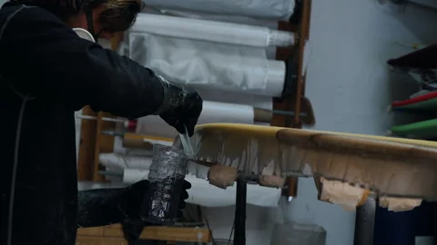 Creative man painting a mask surfboard in a workshop after hours Stock Footage 321584533