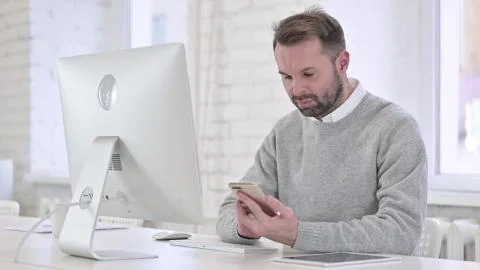 Creative Man Working on Computer and Using Smartphone Foto stock