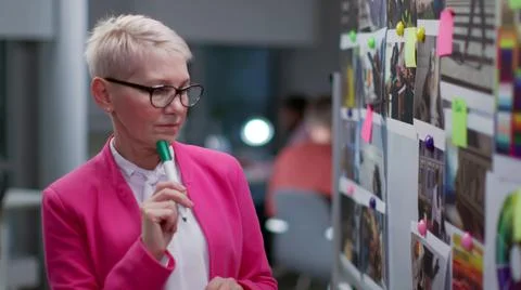 Creative mature woman write notes on board with pictures and notes working in Stock Photos
