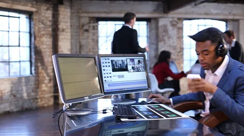 Creative media editor at work. Small team gathering in background to discuss Stock-Footage 32729082