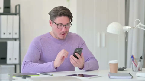 Creative Middle Aged Man Celebrating Success on Smartphone Stockbeeldmateriaal 143563586