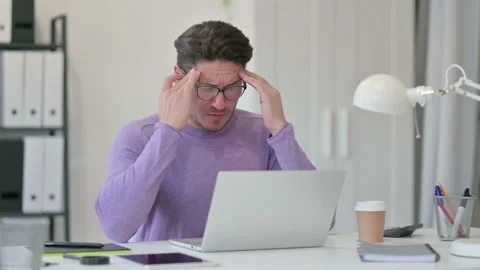 Creative Middle Aged Man with Laptop having Headache in Office Stock Footage 143567992
