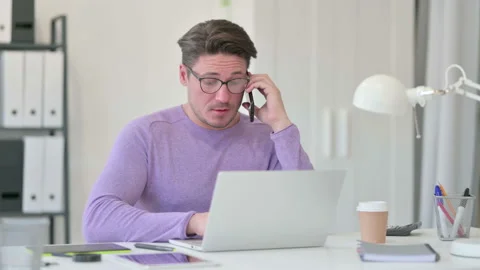 Creative Middle Aged Man with Laptop Talking on Smartphone Video stock 143569571