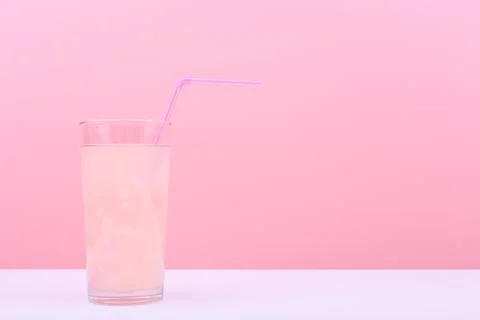 Creative minimal summer composition with pink drink with straw on white table Stock Photos